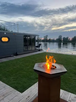 a fire pit in a yard next to a lake at NEW - Little Asia - Stunning Boathouse on a lake Near Amsterdam with Sauna in Vinkeveen