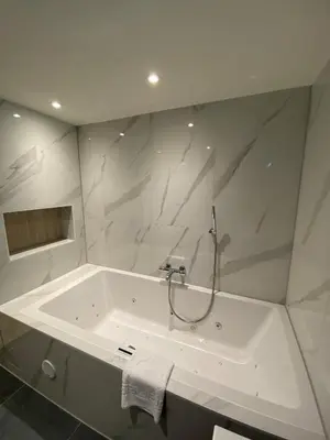 a white bathroom with a bath tub with a sink at Alp de Veenen Hotel in Amstelveen