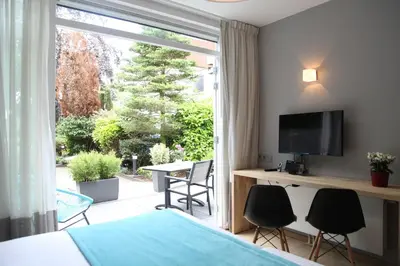 a bedroom with a bed and a television and a table with chairs at Alp de Veenen Hotel in Amstelveen