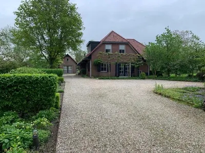 a house with a gravel driveway in front of it at Lovely warm Country home in Breukeleveen