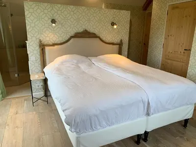 a bedroom with a white bed with a wooden headboard at Lovely warm Country home in Breukeleveen