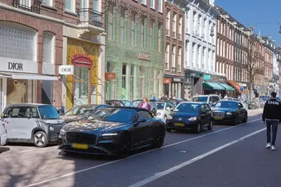 a black car driving down a busy city street at Aadam Wilhelmina Hotel in Amsterdam