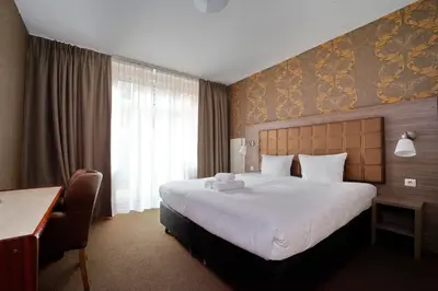a hotel room with a large bed and a desk at Aadam Wilhelmina Hotel in Amsterdam