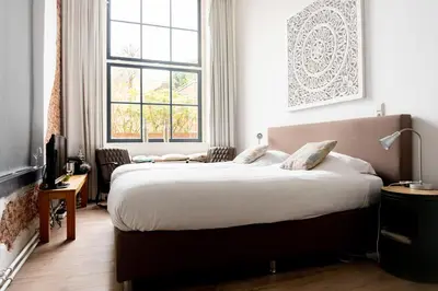 a bedroom with a large bed and a large window at 1001 Nights Boutique Hotel in Haarlem