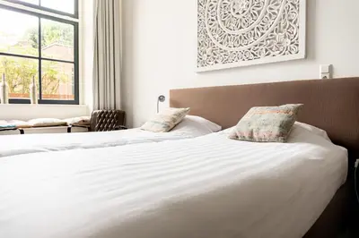a bedroom with two beds with white sheets and pillows at 1001 Nights Boutique Hotel in Haarlem