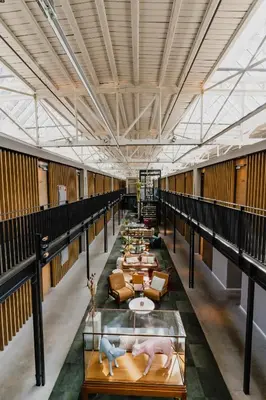a long hallway with tables and couches in a building at Hotel De Hallen in Amsterdam