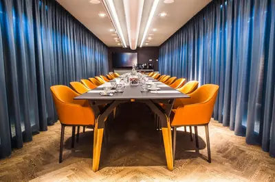 a conference room with a long table and orange chairs at Hotel De Hallen in Amsterdam