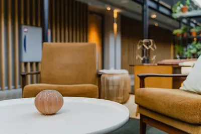 a room with two chairs and a table with a wooden bowl on it at Hotel De Hallen in Amsterdam
