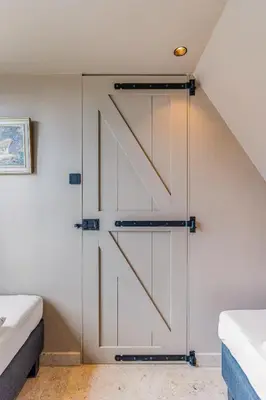 a sliding barn door in a bedroom with two beds at Luxury private farmhouse cottage near Amsterdam plus home cinema in Ilpendam