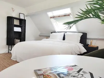 a bedroom with a white bed and a window at Guesthouse at the Amstel river with 2BR 2BA and garden in Amstelveen