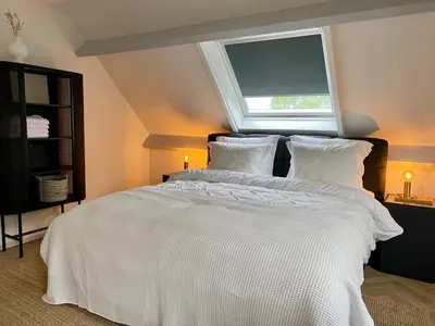 a bedroom with a large white bed with a window at Guesthouse at the Amstel river with 2BR 2BA and garden in Amstelveen