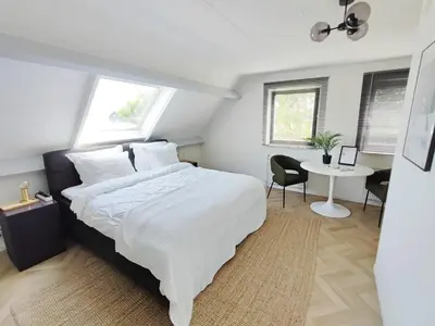 a bedroom with a large white bed and a desk at Guesthouse at the Amstel river with 2BR 2BA and garden in Amstelveen