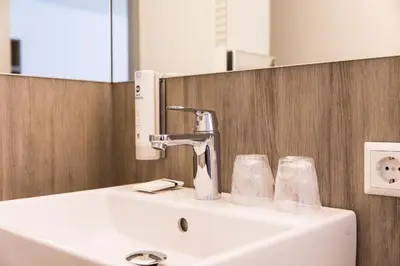a bathroom sink with a faucet and two glasses at Best Western City Hotel Woerden in Woerden
