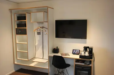 a room with a desk with a computer and a tv at Hotel Hogerhuys - adults only in Noordwijk aan Zee
