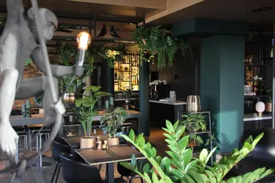 a restaurant with tables and potted plants at Hotel Hogerhuys - adults only in Noordwijk aan Zee