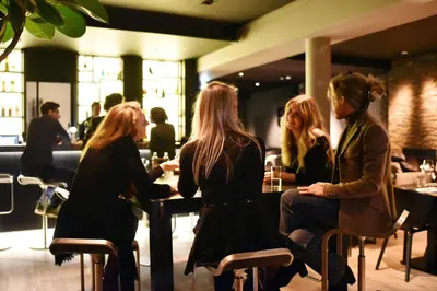 three women sitting at a table in a restaurant at Hotel Hogerhuys - adults only in Noordwijk aan Zee