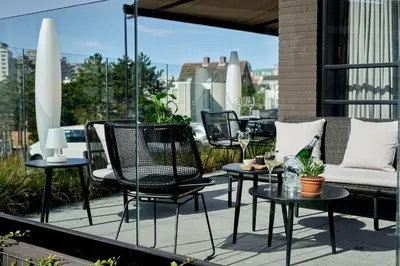 a patio with chairs and tables on a balcony at Hotel Hogerhuys - adults only in Noordwijk aan Zee