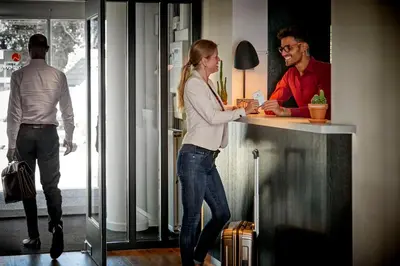 a woman standing at a counter with a man behind it at Hotel Hogerhuys - adults only in Noordwijk aan Zee