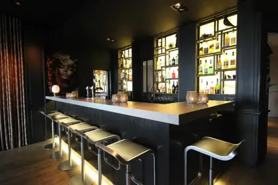 a bar with stools in a room with windows at Hotel Hogerhuys - adults only in Noordwijk aan Zee
