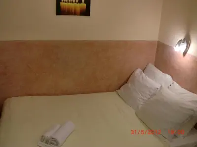 a bed with a white pillow and a roll on it at Budget Hotel Neutraal in Amsterdam