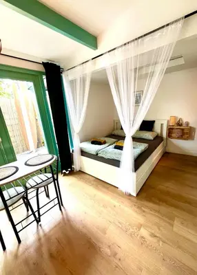 a bedroom with a bed with curtains and a table at Cozy comfortable house with jacuzzi & private garden near Amsterdam in Vijfhuizen