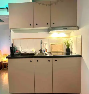 a kitchen with white cabinets and a sink at Cozy comfortable house with jacuzzi & private garden near Amsterdam in Vijfhuizen