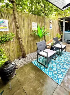 a patio with chairs and a grill and a fence at Cozy comfortable house with jacuzzi & private garden near Amsterdam in Vijfhuizen