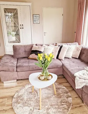 a living room with a couch and a table with flowers at Nordseeperle Dirkshorn Nordholland, mit Klimaanlage und Sauna in Dirkshorn