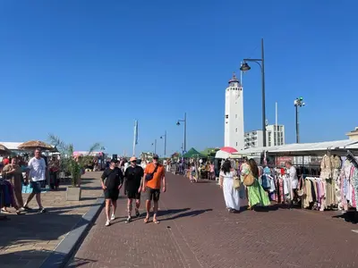 a group of people walking on a sidewalk near a market at Strandhuis aan zee in Noordwijk