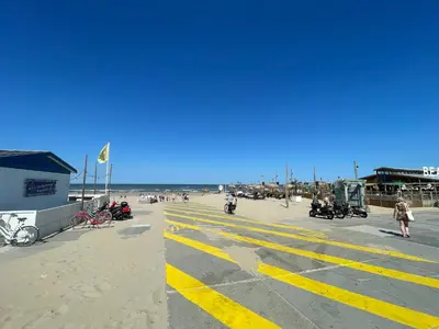 a parking lot with motorcycles and people on the beach at Strandhuis aan zee in Noordwijk