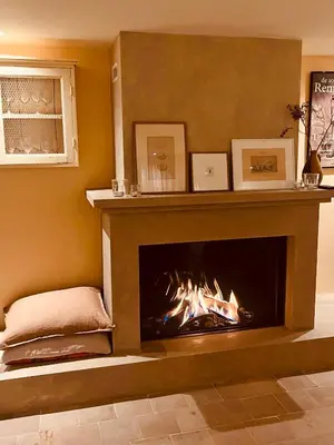 a fireplace in a living room with a fire at Cottage Het Beukenootje in Aerdenhout