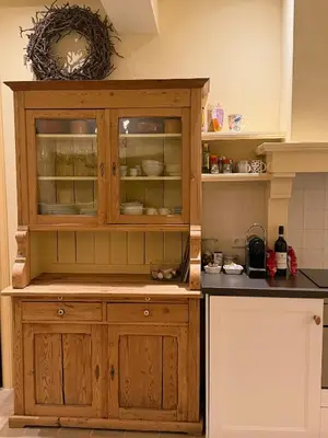 a wooden cabinet with glass doors in a kitchen at Cottage Het Beukenootje in Aerdenhout