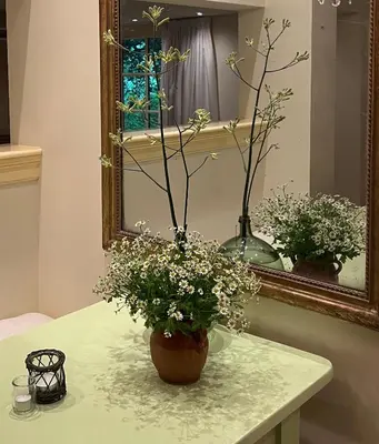 a vase of flowers on a table in front of a mirror at Cottage Het Beukenootje in Aerdenhout