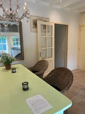 a dining room with a table and wicker chairs at Cottage Het Beukenootje in Aerdenhout