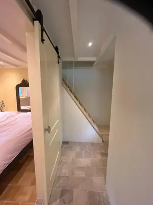 a room with a bed and a sliding door with a staircase at Cottage Het Beukenootje in Aerdenhout