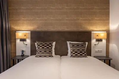 two beds in a room with two lamps at Hotel Amsterdam De Roode Leeuw in Amsterdam