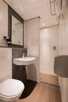 a bathroom with a white toilet and a sink at Hotel Amsterdam De Roode Leeuw in Amsterdam