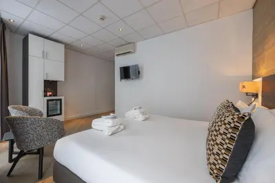 a hotel room with a large bed and a chair at Hotel Amsterdam De Roode Leeuw in Amsterdam