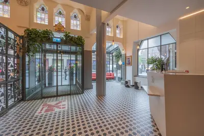 a lobby with a glass door and a tile floor at Hotel Amsterdam De Roode Leeuw in Amsterdam