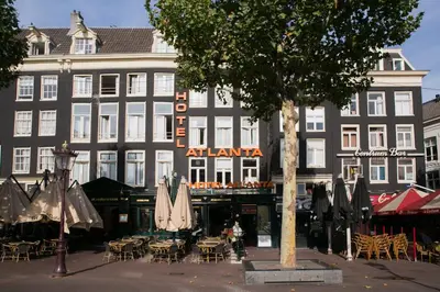 a building with tables and umbrellas in front of it at Hotel Atlanta in Amsterdam