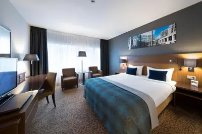 a hotel room with a bed and a flat screen tv at Bilderberg Garden Hotel in Amsterdam