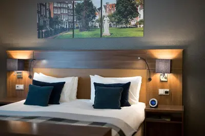 a bedroom with a large bed with blue and white pillows at Bilderberg Garden Hotel in Amsterdam