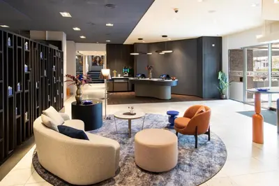 a lobby with chairs and tables and a kitchen at Bilderberg Garden Hotel in Amsterdam