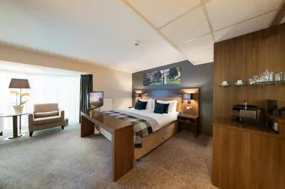 a large hotel room with a bed and a chair at Bilderberg Garden Hotel in Amsterdam