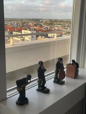 a group of figurines on a window sill looking out at a city at North Sea Spirit in Zandvoort