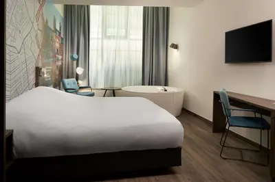 a hotel room with a bed and a desk and a tub at Inntel Hotels Amsterdam Centre in Amsterdam