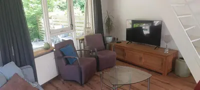 a living room with two chairs and a television at Cappuccetto Rosso in Nieuwe-Niedorp