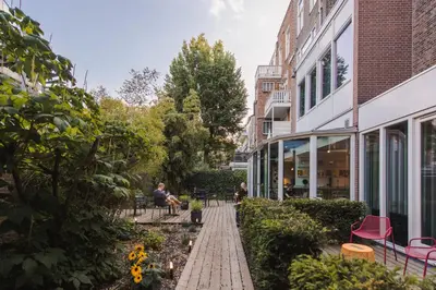 a garden with people sitting on benches in front of a building at Conscious Hotel Museum Square in Amsterdam