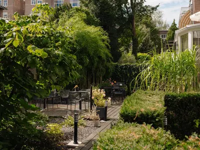a garden with chairs and tables and trees at Conscious Hotel Museum Square in Amsterdam