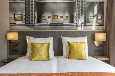 a bedroom with a white bed with two yellow pillows at Leonardo Hotel Amsterdam Museum Quarter in Amsterdam